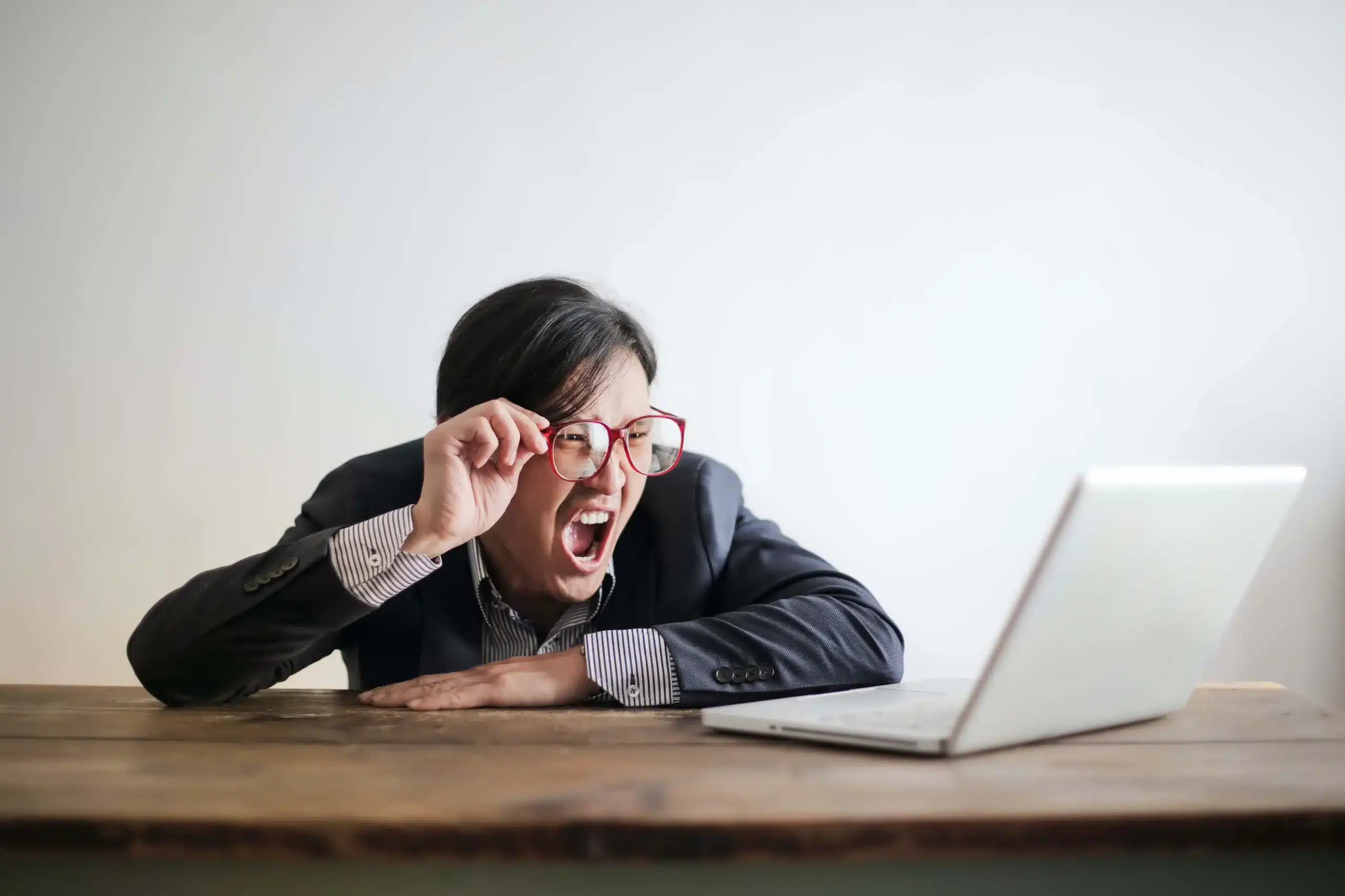 man with glasses screaming at his computer
